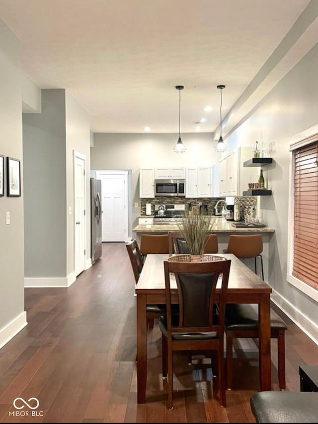 dining room with baseboards, dark wood finished floors, and recessed lighting