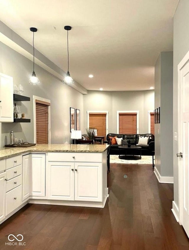 kitchen featuring white cabinets, dark wood-style flooring, a peninsula, light stone countertops, and open shelves