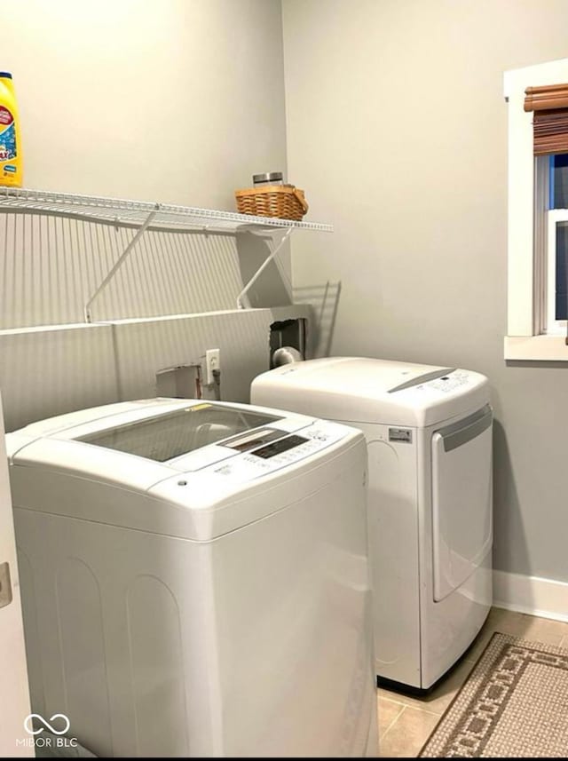 laundry area with laundry area, light tile patterned flooring, independent washer and dryer, and baseboards