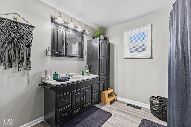 bathroom with vanity, wood finished floors, visible vents, and baseboards