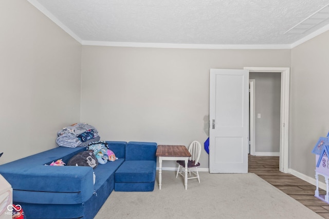 living area with baseboards, ornamental molding, a textured ceiling, and wood finished floors