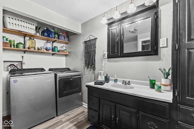 laundry room featuring washer and dryer, a sink, and light wood-style flooring