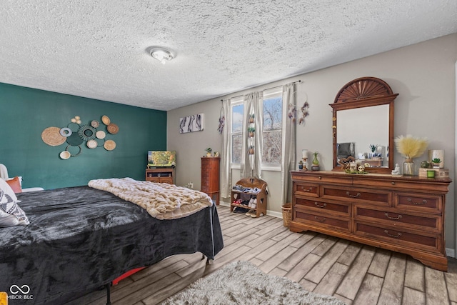 bedroom featuring a textured ceiling, light wood finished floors, and baseboards