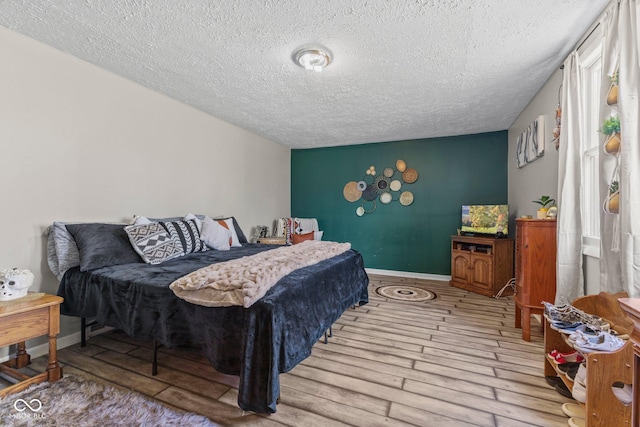 bedroom featuring a textured ceiling, baseboards, and wood finished floors