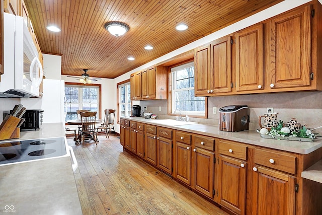 kitchen featuring white microwave, brown cabinetry, and a sink