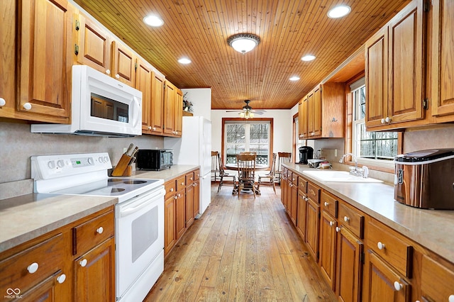 kitchen featuring white appliances, a sink, wood ceiling, light countertops, and light wood finished floors