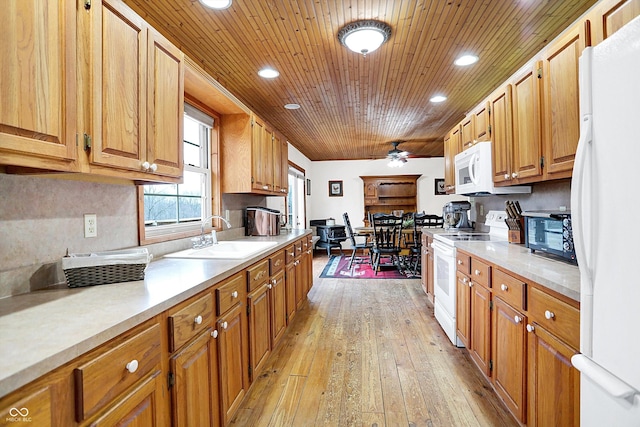 kitchen featuring white appliances, light countertops, a sink, and light wood finished floors