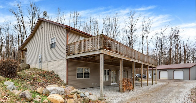 exterior space featuring brick siding, a detached garage, a deck, and an outbuilding