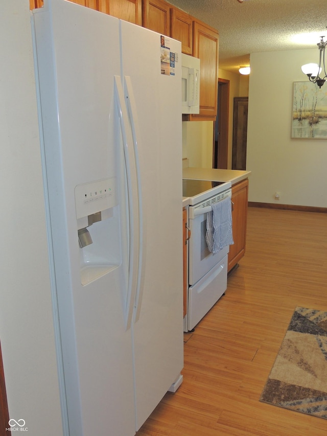 kitchen featuring white appliances, baseboards, light countertops, a textured ceiling, and light wood-type flooring