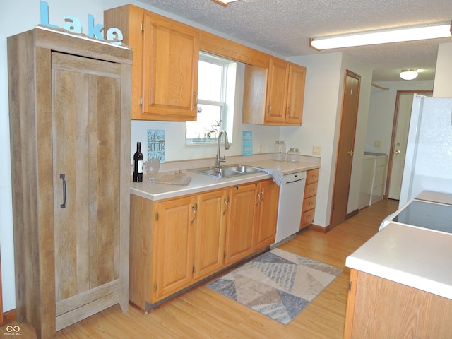 kitchen with a sink, light wood-type flooring, white appliances, and light countertops