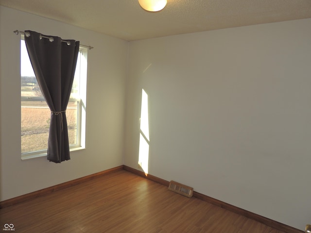 empty room featuring plenty of natural light, baseboards, and wood finished floors