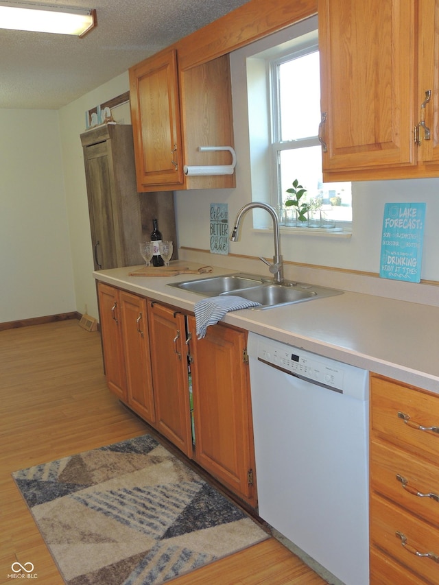 kitchen featuring light wood-style flooring, a sink, light countertops, a textured ceiling, and dishwasher