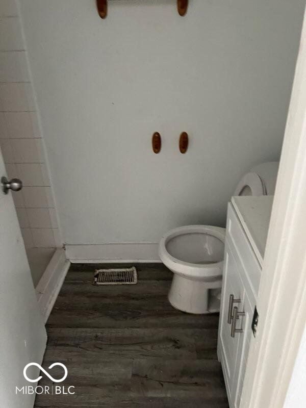 bathroom featuring a shower, visible vents, toilet, wood finished floors, and baseboards