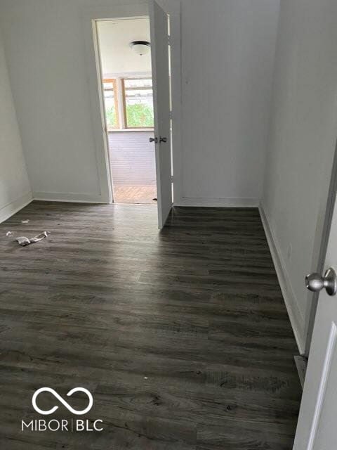 corridor featuring baseboards and dark wood-style flooring