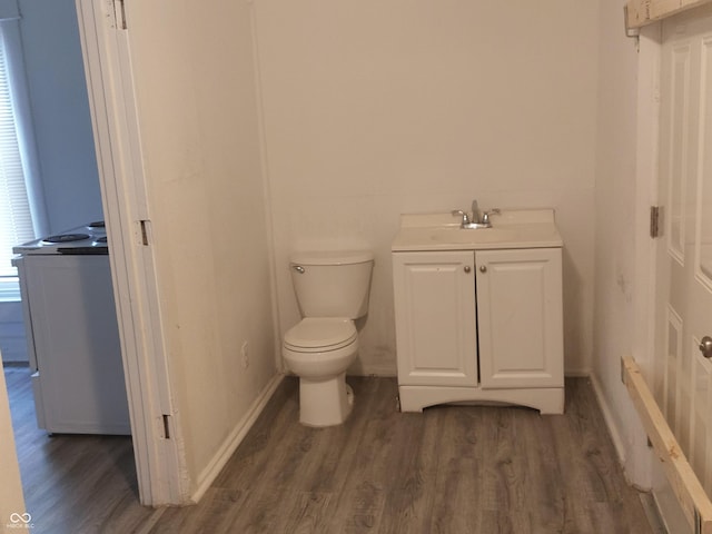 half bath featuring toilet, baseboards, wood finished floors, and vanity