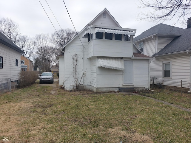 back of property with entry steps, fence, and a lawn