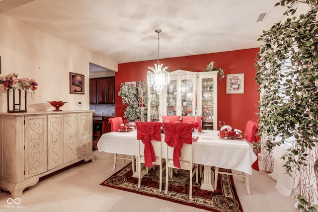 dining area with light carpet, visible vents, and a chandelier