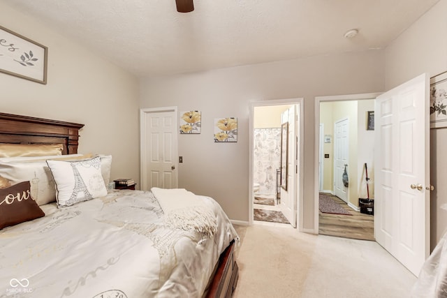 bedroom featuring light carpet, connected bathroom, a textured ceiling, ceiling fan, and baseboards