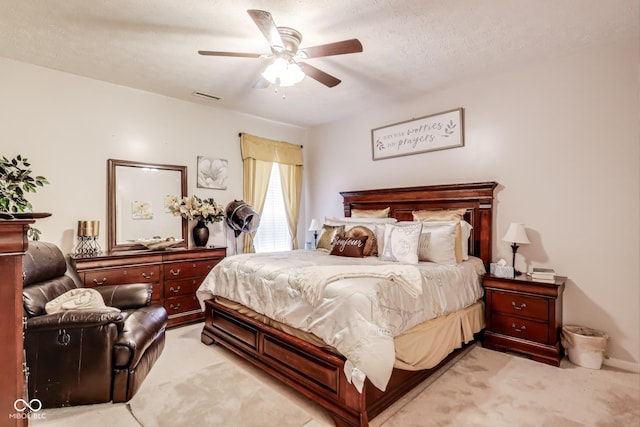 bedroom with a ceiling fan, light colored carpet, visible vents, and a textured ceiling