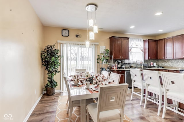 kitchen with pendant lighting, tasteful backsplash, light countertops, stainless steel dishwasher, and baseboards