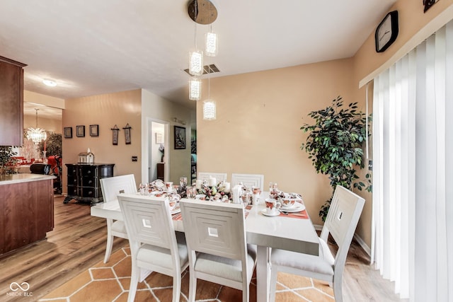 dining area with light wood finished floors and a chandelier