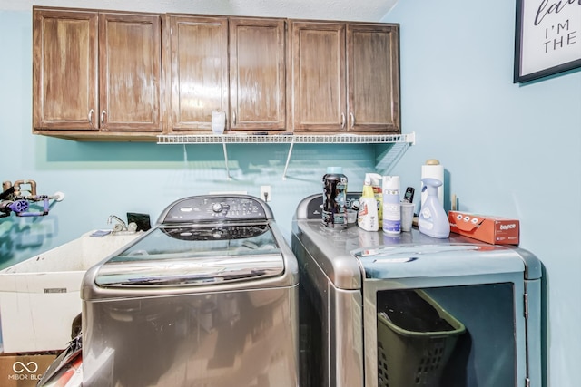 laundry area featuring separate washer and dryer, a sink, and cabinet space