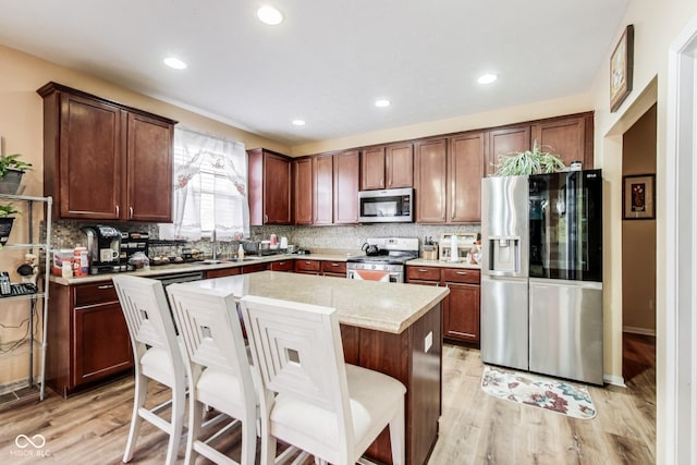 kitchen featuring light wood-type flooring, tasteful backsplash, stainless steel appliances, and a center island