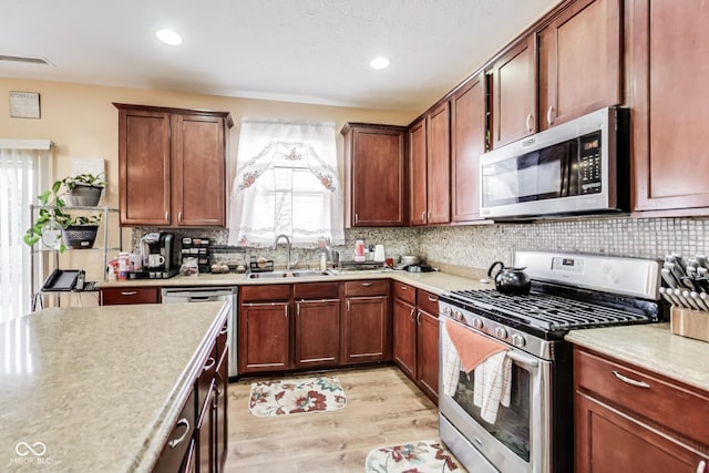 kitchen featuring stainless steel appliances, a sink, visible vents, light countertops, and tasteful backsplash