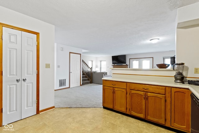 kitchen with a peninsula, visible vents, open floor plan, light countertops, and brown cabinets