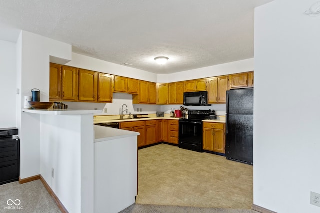 kitchen with brown cabinets, black appliances, light countertops, and a sink