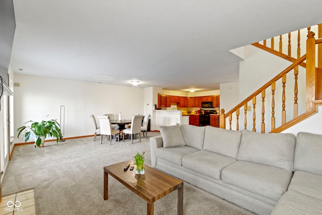 carpeted living area with stairs and baseboards