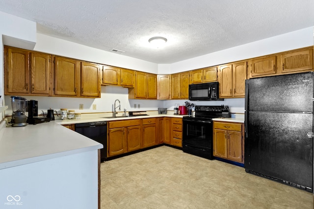 kitchen with light countertops, visible vents, brown cabinetry, a sink, and black appliances