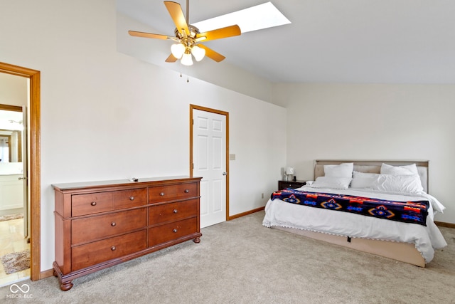 bedroom with carpet, ensuite bathroom, ceiling fan, vaulted ceiling with skylight, and baseboards