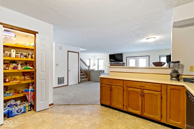 kitchen with brown cabinets, light countertops, visible vents, open floor plan, and a peninsula