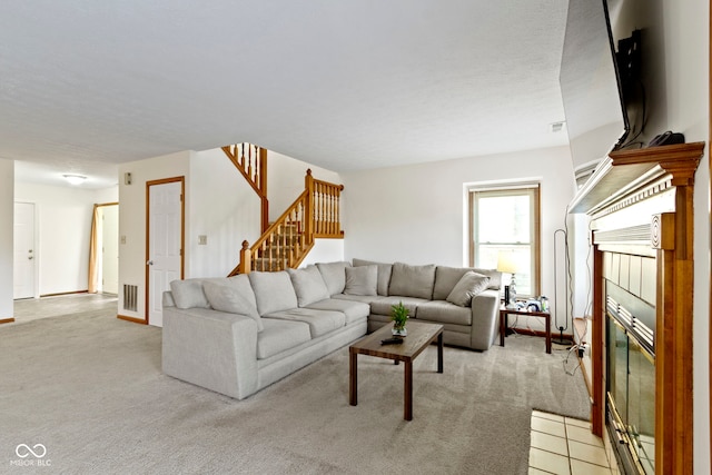 living area featuring stairs, visible vents, light colored carpet, and a tile fireplace