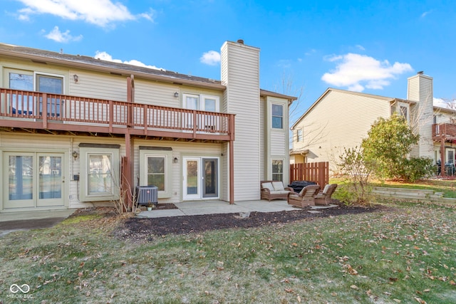 rear view of property featuring central AC unit, a balcony, a yard, a chimney, and a patio area