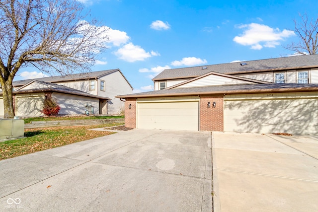 view of front of property featuring driveway, brick siding, and a shingled roof