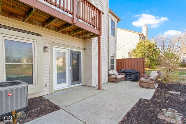 view of patio with central AC, fence, and a balcony