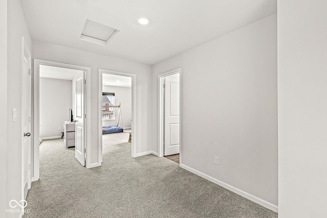 spare room featuring attic access, baseboards, and carpet flooring