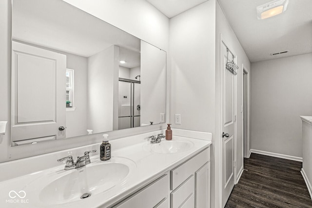 bathroom with double vanity, wood finished floors, a sink, and baseboards