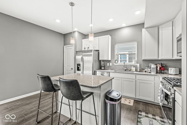 kitchen with dark wood-type flooring, a kitchen island, stainless steel appliances, and a sink