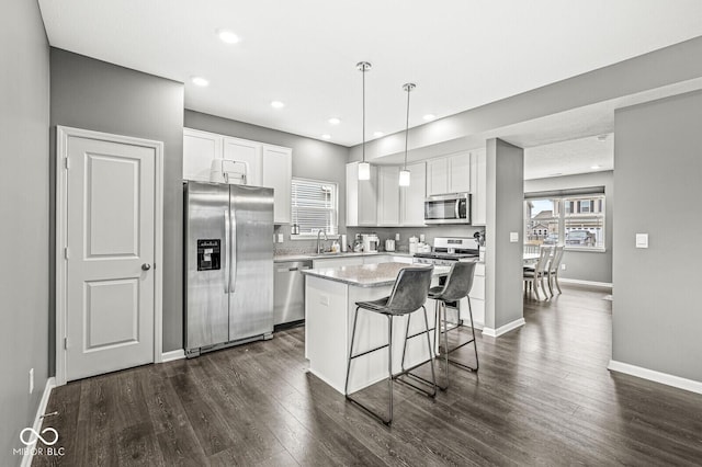 kitchen featuring dark wood-style flooring, a sink, white cabinets, appliances with stainless steel finishes, and a center island