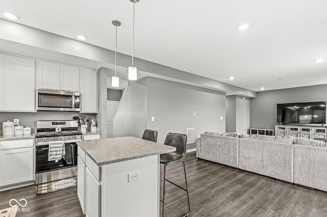 kitchen with dark wood-style floors, a breakfast bar area, stainless steel appliances, open floor plan, and white cabinetry