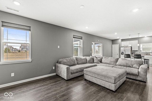 living room with dark wood-style floors, recessed lighting, visible vents, and baseboards