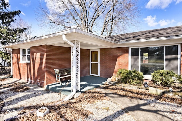 entrance to property featuring covered porch and brick siding