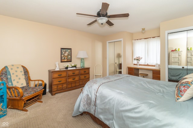 bedroom featuring two closets, built in desk, carpet floors, and ceiling fan