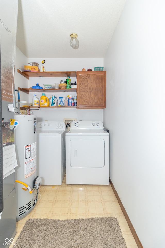 clothes washing area featuring baseboards, light floors, water heater, cabinet space, and separate washer and dryer