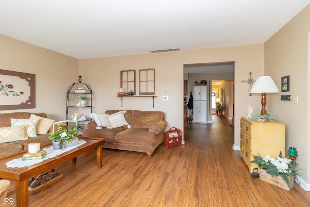 living room featuring wood finished floors, visible vents, and baseboards