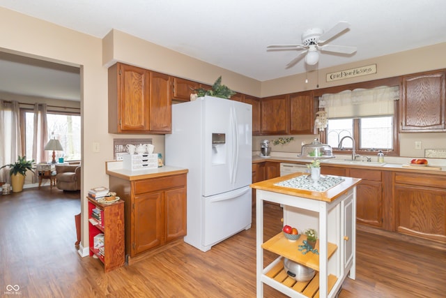 kitchen with open shelves, light wood-style flooring, white fridge with ice dispenser, and a sink