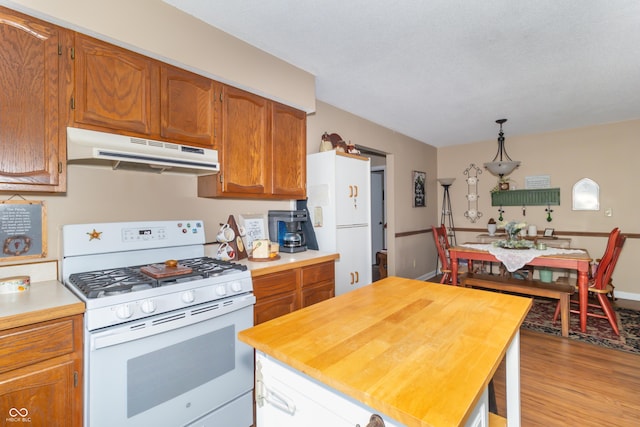 kitchen featuring baseboards, under cabinet range hood, light wood-type flooring, white range with gas stovetop, and brown cabinets